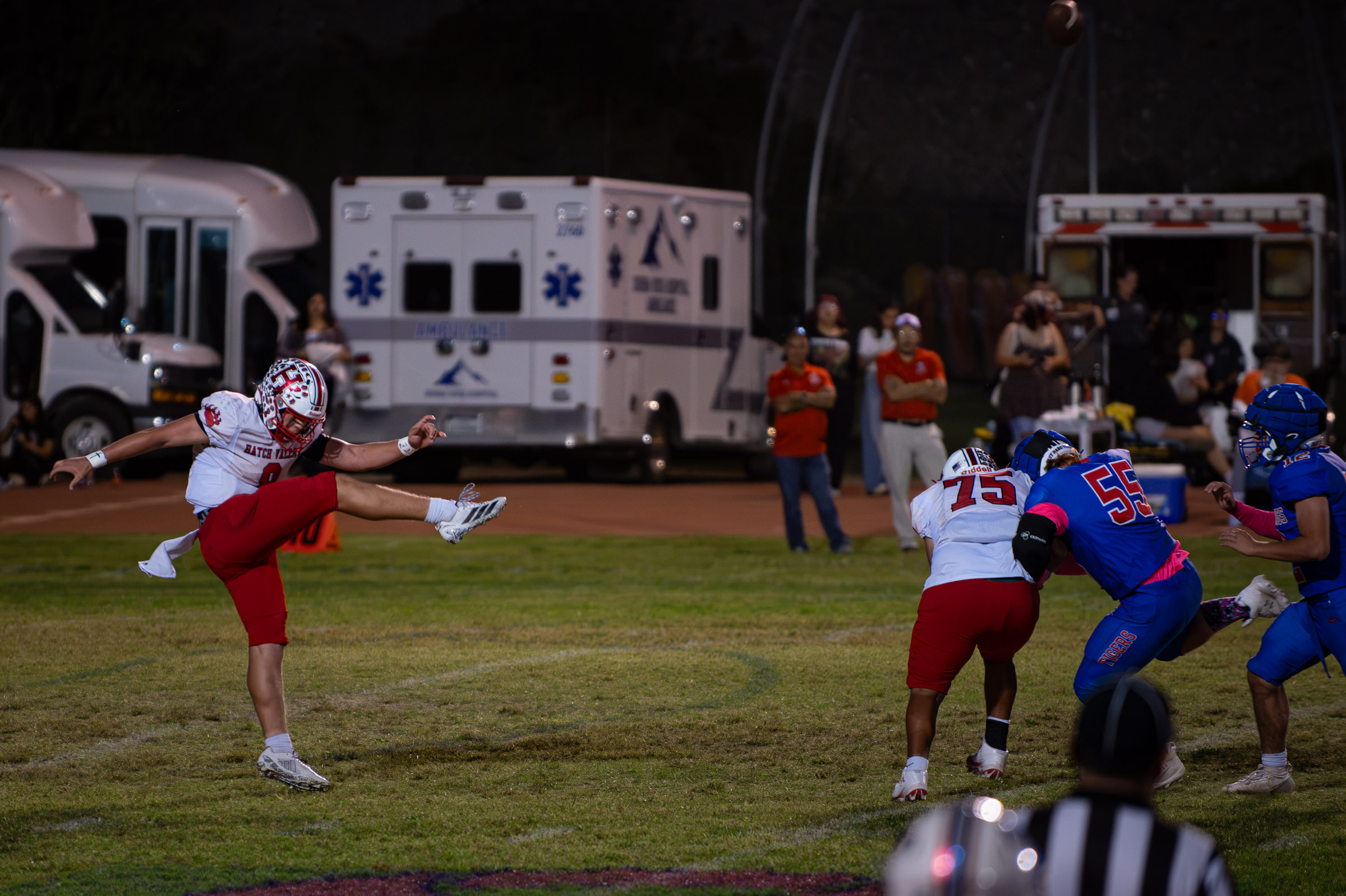 Hatch Valley punter Peet Bothma (#8) kicks the ball as Hot Springs players rush during a punt.
